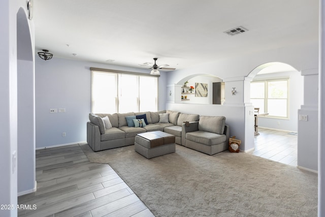 living room featuring ceiling fan, plenty of natural light, and light hardwood / wood-style floors