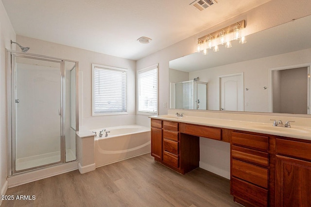18123 W Lundberg St, Surprise, AZ 85388 - bathroom featuring wood finished floors, a stall shower, double vanity, and a garden tub