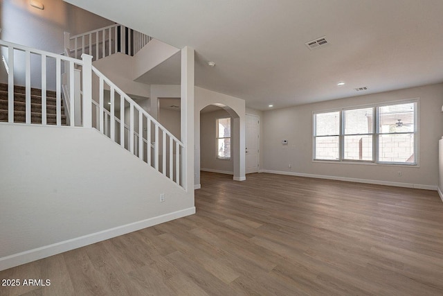 18123 W Lundberg St, Surprise, AZ 85388 - unfurnished living room with arched walkways, wood finished floors, stairs, healthy amount of natural light, and recessed lighting