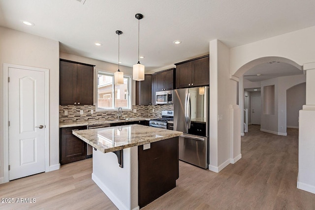 18123 W Lundberg St, Surprise, AZ 85388 - kitchen with stainless steel appliances, a sink, dark brown cabinetry, arched walkways, and recessed lighting