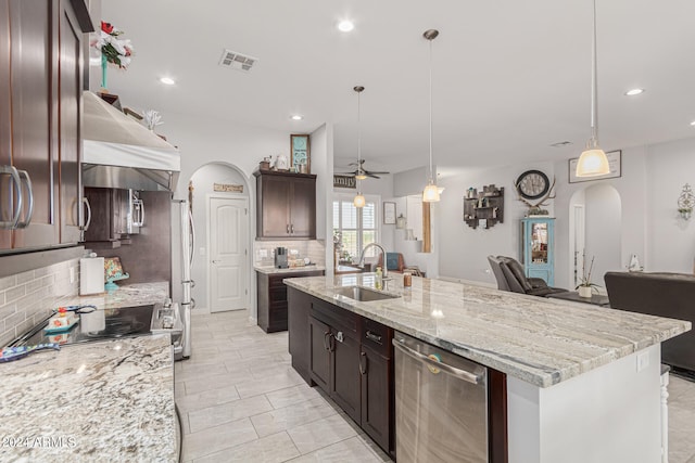 kitchen with ceiling fan, pendant lighting, sink, a center island with sink, and backsplash