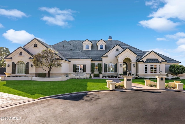 french country home featuring a front lawn and stucco siding