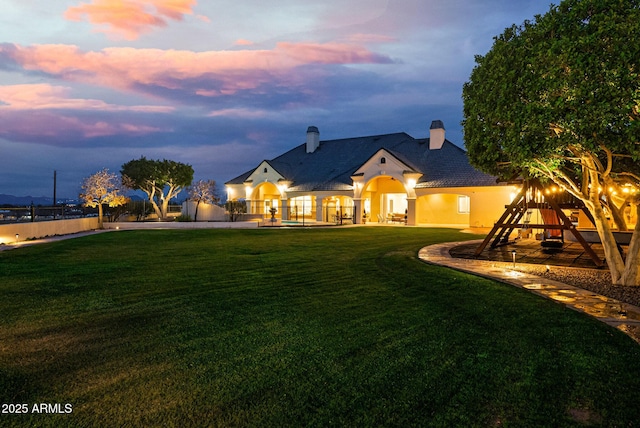 view of front of house with a playground and a lawn