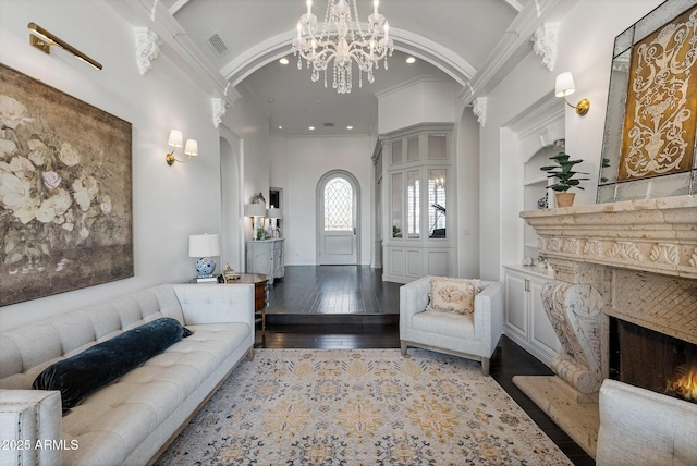 living room with ornamental molding, vaulted ceiling, light wood-type flooring, and built in shelves