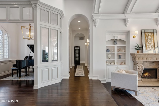 hallway featuring an inviting chandelier, built in shelves, dark hardwood / wood-style floors, and beamed ceiling