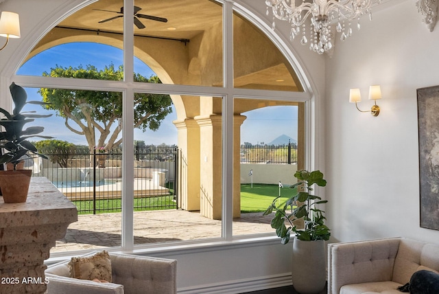 entryway with plenty of natural light and ceiling fan with notable chandelier