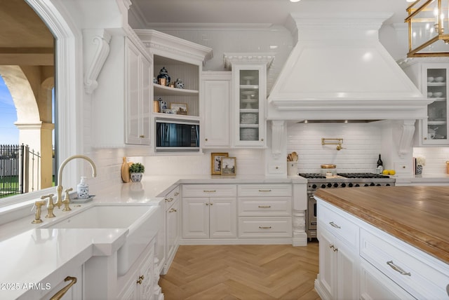 kitchen featuring white cabinetry, black microwave, custom exhaust hood, light parquet floors, and stainless steel range