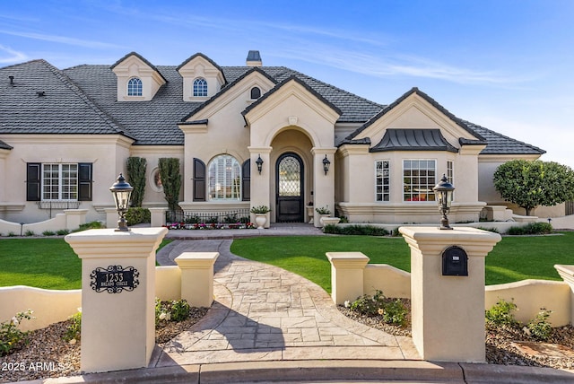 french country home featuring a front yard, a tile roof, a chimney, and stucco siding