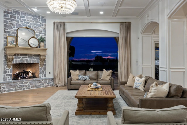 living room with coffered ceiling, a fireplace, a notable chandelier, and wood-type flooring