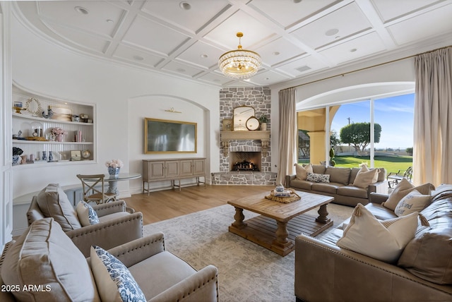 living room featuring coffered ceiling, light wood-type flooring, built in features, a notable chandelier, and a fireplace