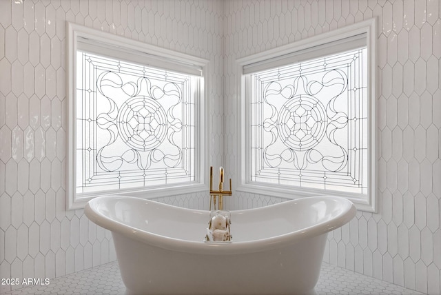 bathroom with a bathing tub, tile patterned flooring, and tile walls