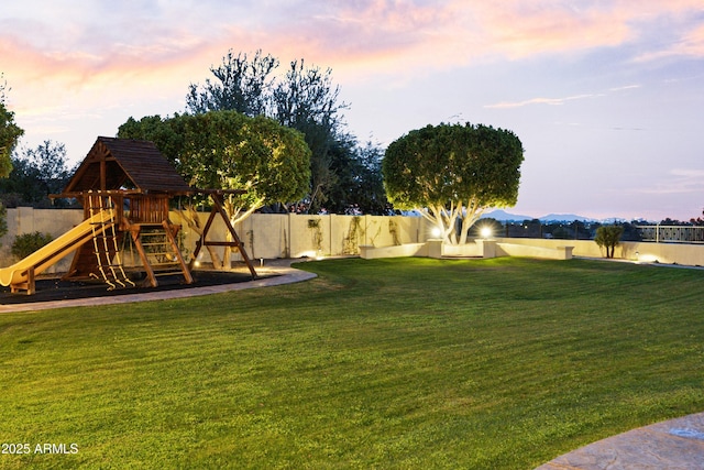 yard at dusk featuring a playground