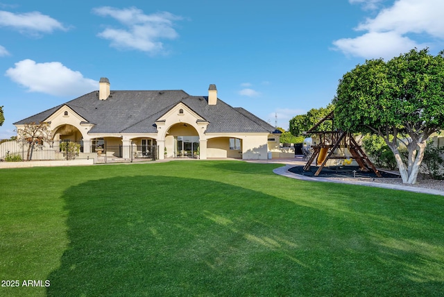 back of house featuring a playground and a yard