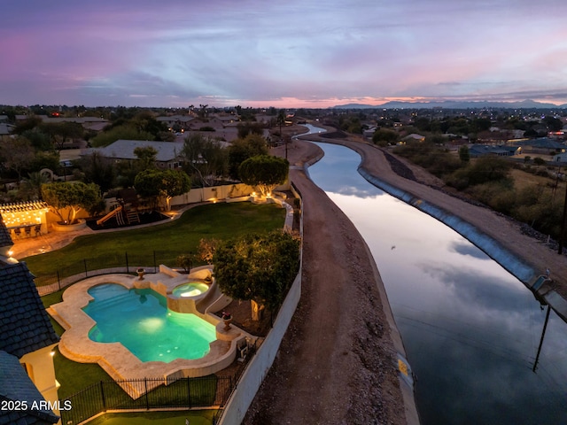 pool at dusk featuring a lawn