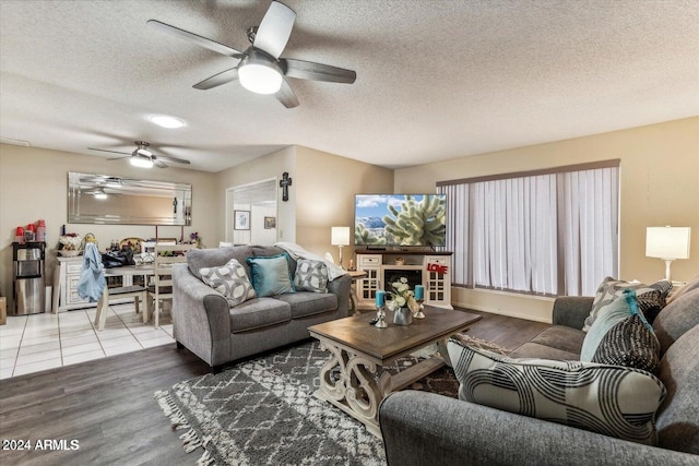 living room with ceiling fan, a textured ceiling, and light hardwood / wood-style flooring