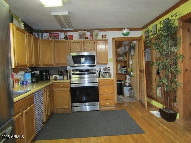 kitchen with light wood-type flooring, appliances with stainless steel finishes, and light countertops