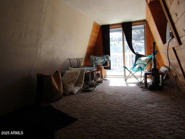 carpeted bedroom with access to exterior and wood walls