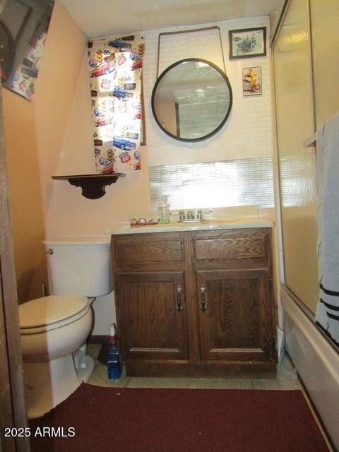 full bath with toilet, vanity, and bath / shower combo with glass door