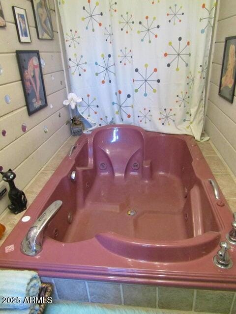 bathroom featuring wooden walls and a jetted tub