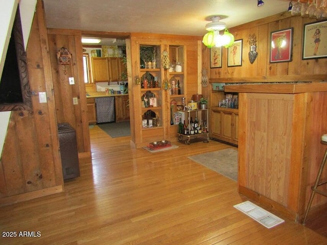 interior space featuring visible vents, light wood-style flooring, and wood walls