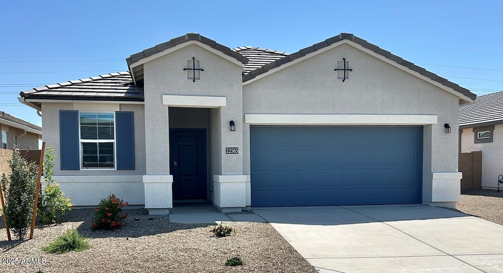 view of front of home with a tiled roof, an attached garage, driveway, and stucco siding