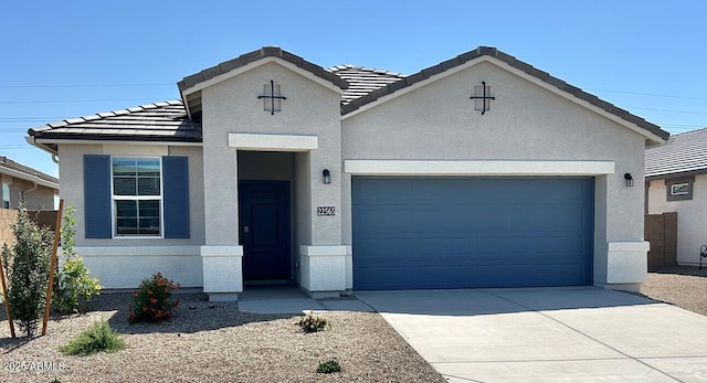 view of front of home with a tiled roof, an attached garage, driveway, and stucco siding