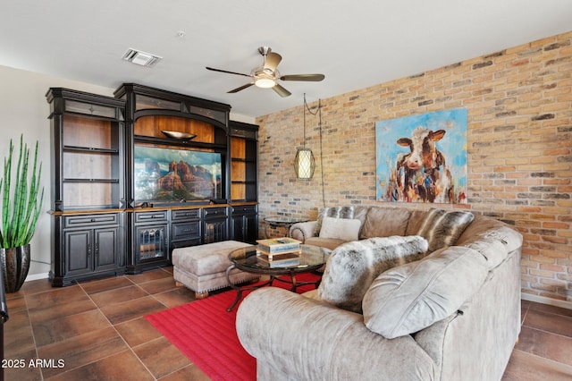 tiled living room featuring ceiling fan and brick wall