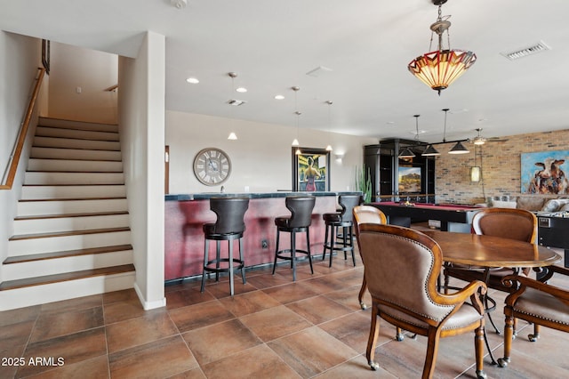 dining space featuring brick wall and bar