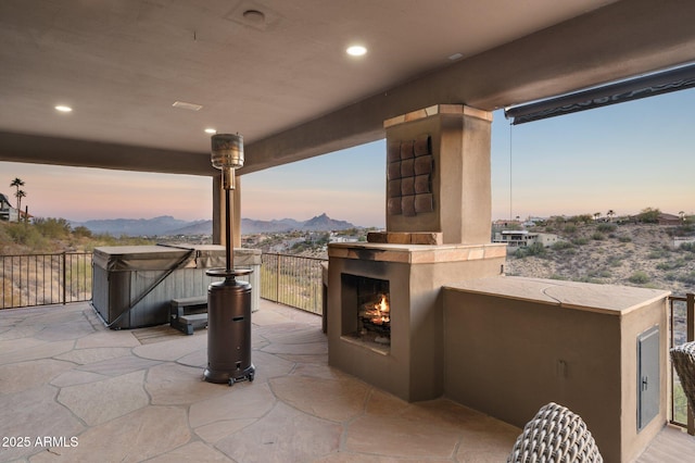 patio terrace at dusk with exterior fireplace and a mountain view