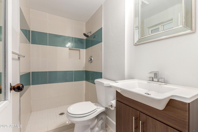 full bathroom featuring toilet, a tile shower, and vanity