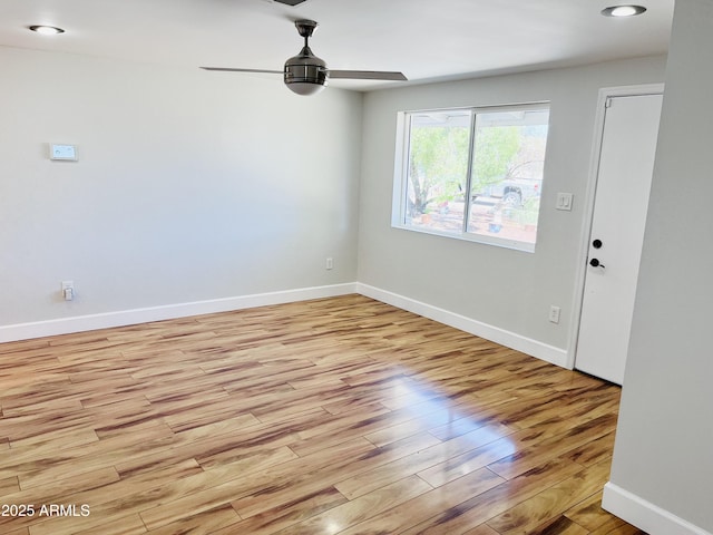 spare room with ceiling fan, light wood-style flooring, and baseboards