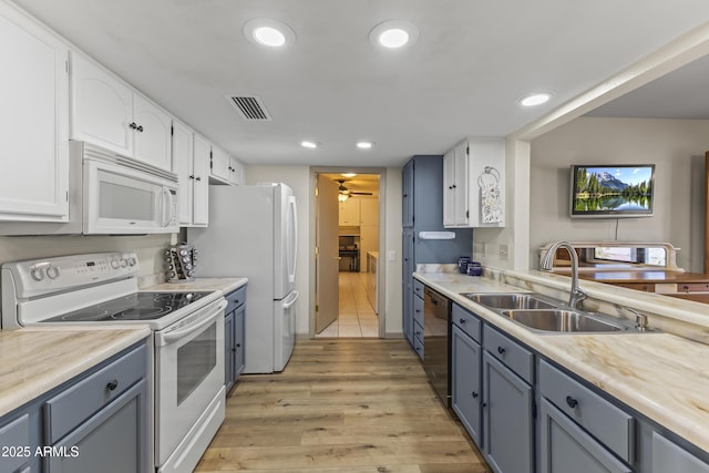 kitchen with sink, white appliances, light hardwood / wood-style flooring, and white cabinets