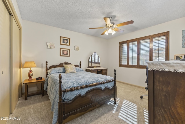 carpeted bedroom with ceiling fan, a closet, and a textured ceiling