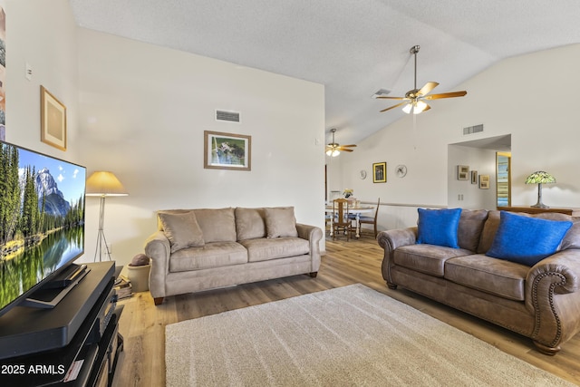 living room featuring ceiling fan, hardwood / wood-style floors, a textured ceiling, and high vaulted ceiling