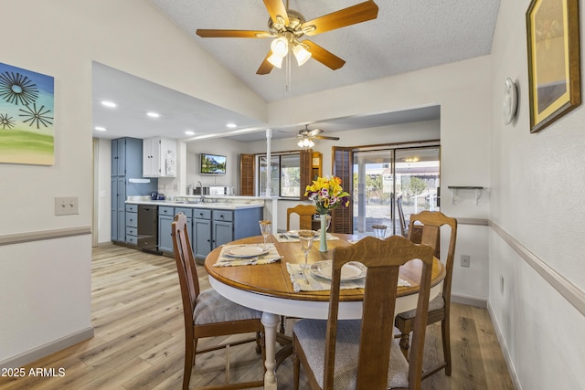 dining space featuring vaulted ceiling, sink, a textured ceiling, and light wood-type flooring