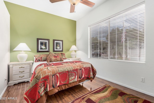 bedroom with a ceiling fan, wood finished floors, and baseboards