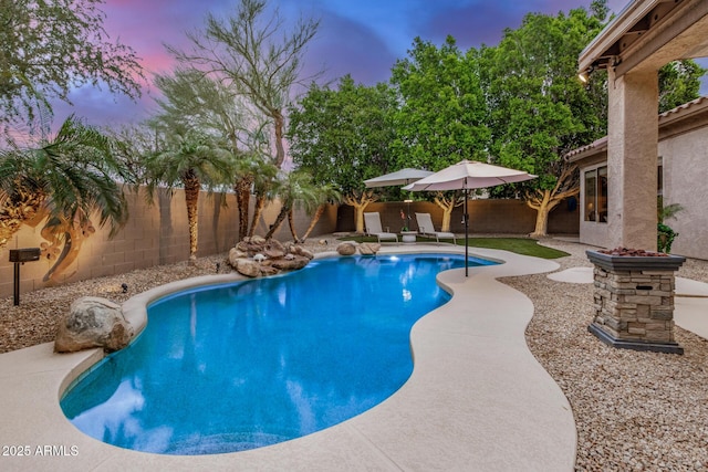 pool at dusk with a patio area, a fenced backyard, and a fenced in pool