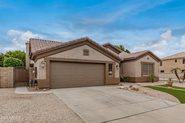 mediterranean / spanish home featuring stucco siding, driveway, a gate, a garage, and a tiled roof