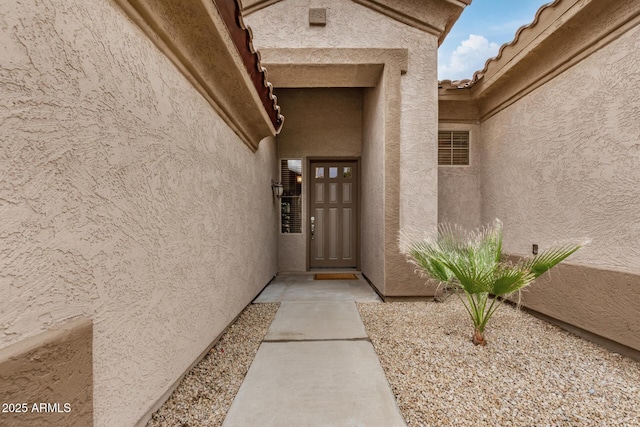 entrance to property with stucco siding and a tiled roof