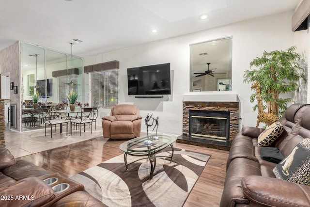 living room featuring a ceiling fan, wood finished floors, visible vents, recessed lighting, and a fireplace