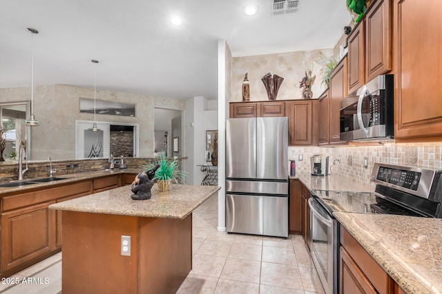 kitchen with visible vents, a center island, brown cabinetry, stainless steel appliances, and a sink