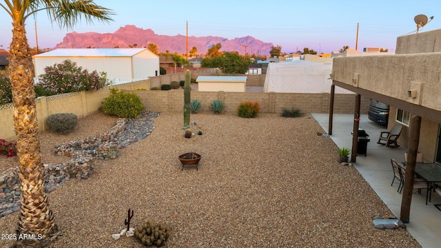 yard at dusk featuring a mountain view and a patio area