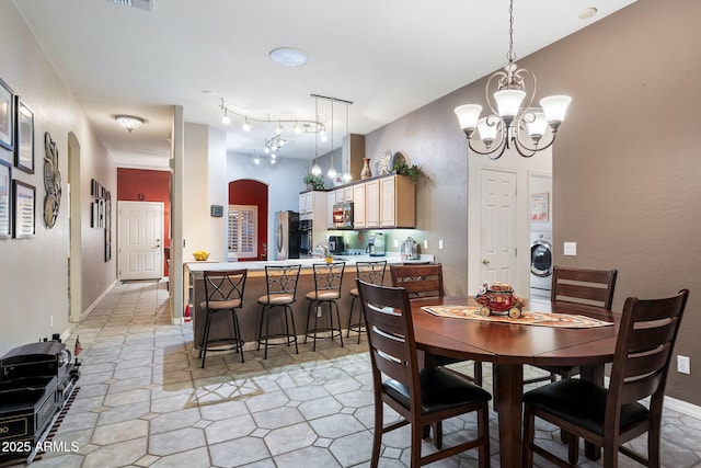 dining space featuring an inviting chandelier and washer / dryer