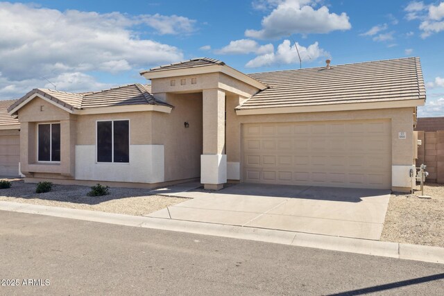view of front of house with stucco siding, a tile roof, a garage, and concrete driveway