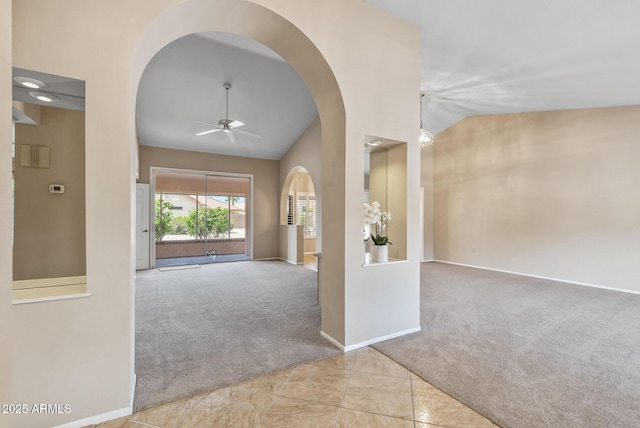 foyer with lofted ceiling, a ceiling fan, arched walkways, carpet floors, and baseboards
