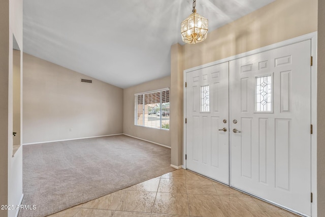 entrance foyer featuring tile patterned floors, a chandelier, carpet, lofted ceiling, and visible vents