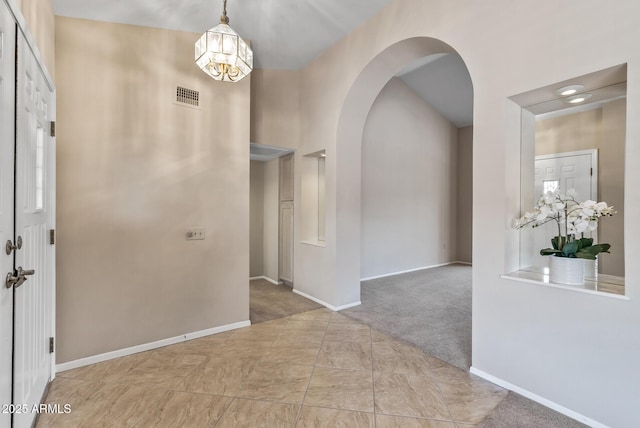 entrance foyer featuring arched walkways, an inviting chandelier, visible vents, and baseboards