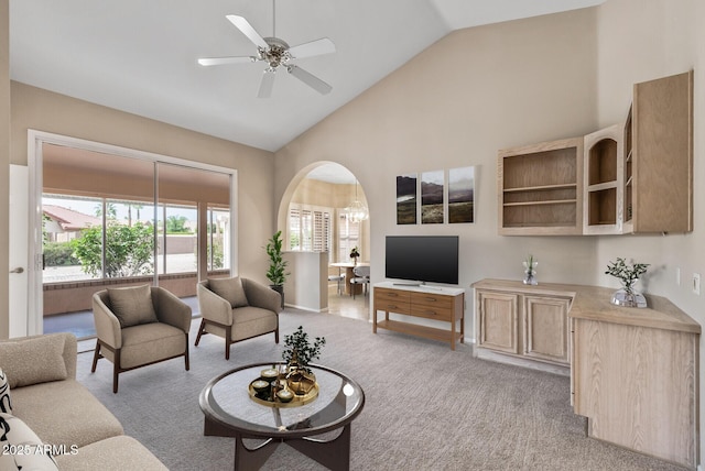carpeted living room featuring high vaulted ceiling, arched walkways, and a ceiling fan