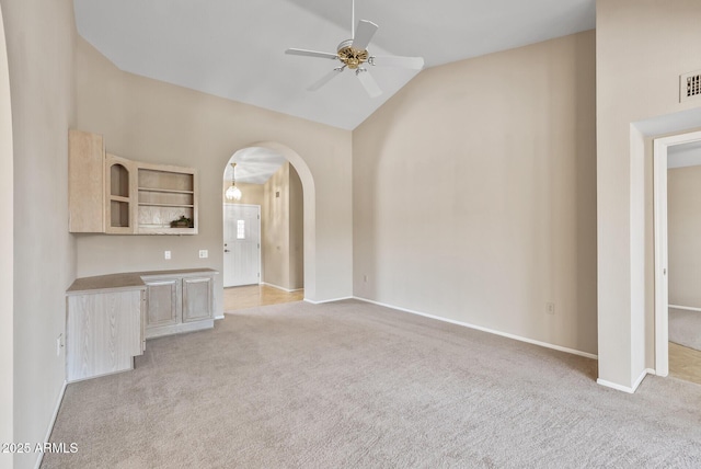 unfurnished living room with vaulted ceiling, visible vents, a ceiling fan, and light carpet
