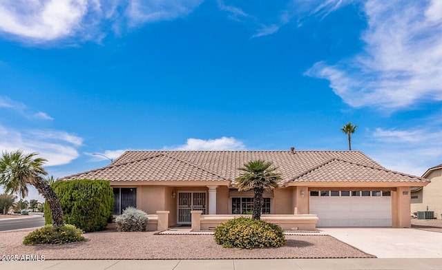view of front of house featuring a tile roof, concrete driveway, an attached garage, cooling unit, and stucco siding
